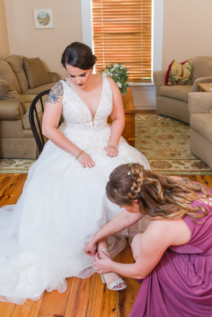 bridesmaid putting on bride's shoes