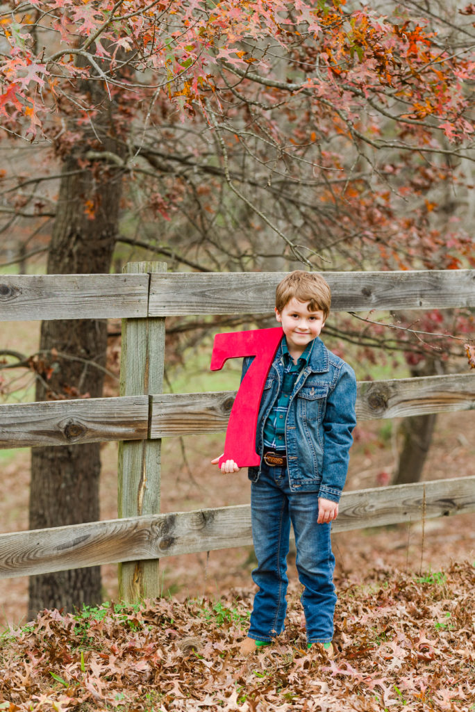 child beside fence holding number seven