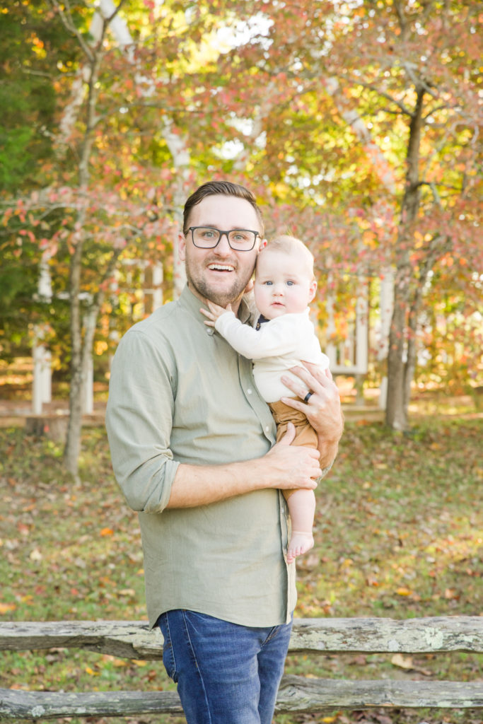 father holding child in fall foliage