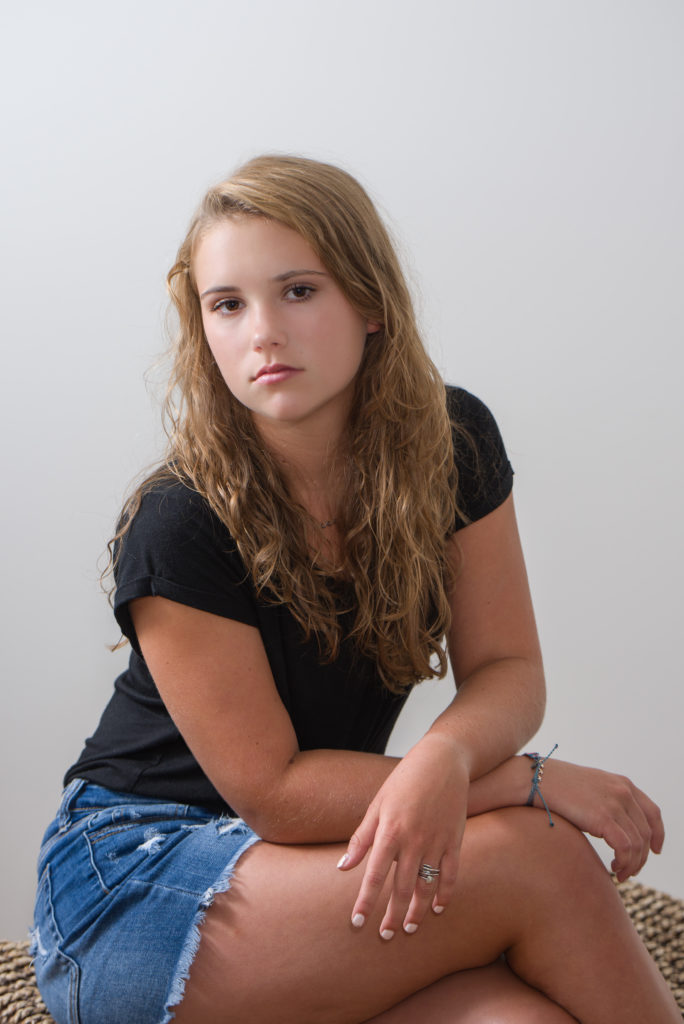 female portrait sitting with arms crossed over knees