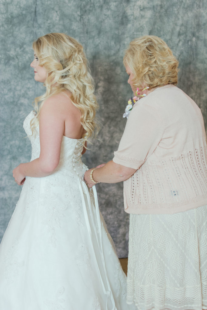 mother of the bride helping bride with dress
