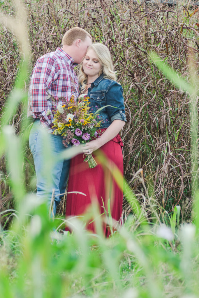 engaged couple nuzzling in field