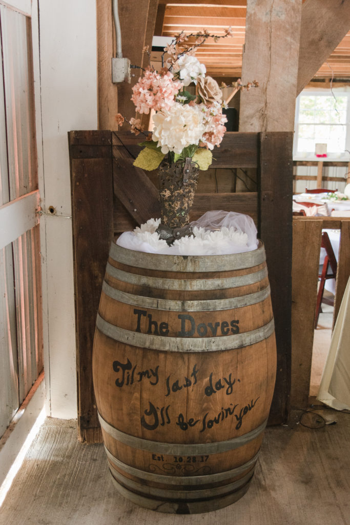 wooden barrel with flower arrangement as rustic wedding reception idea