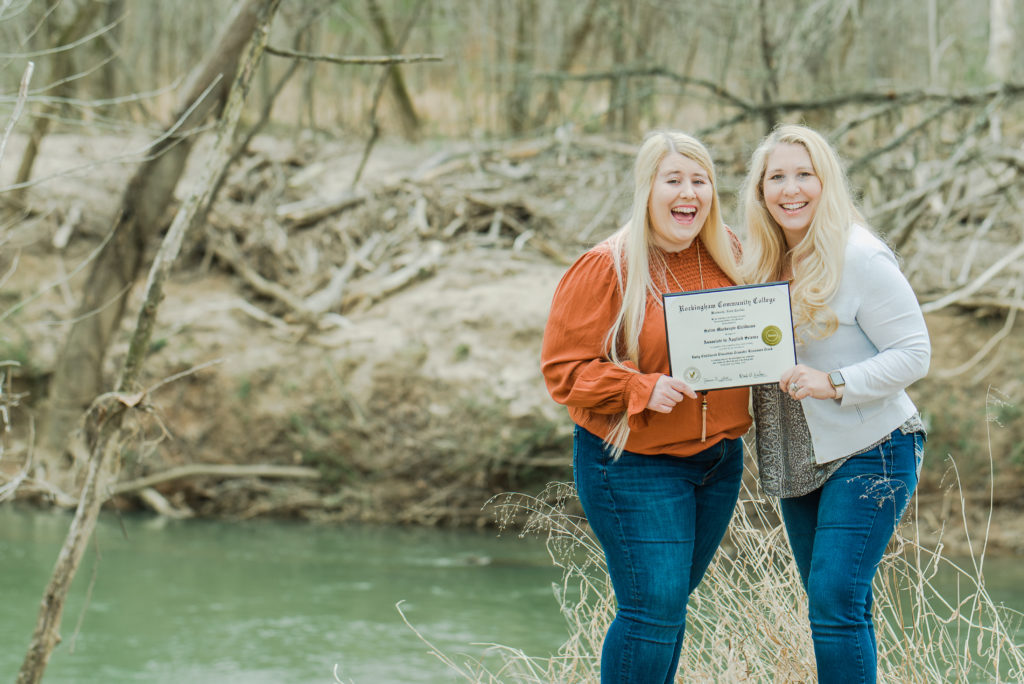 senior with mom holding diploma on riverbank