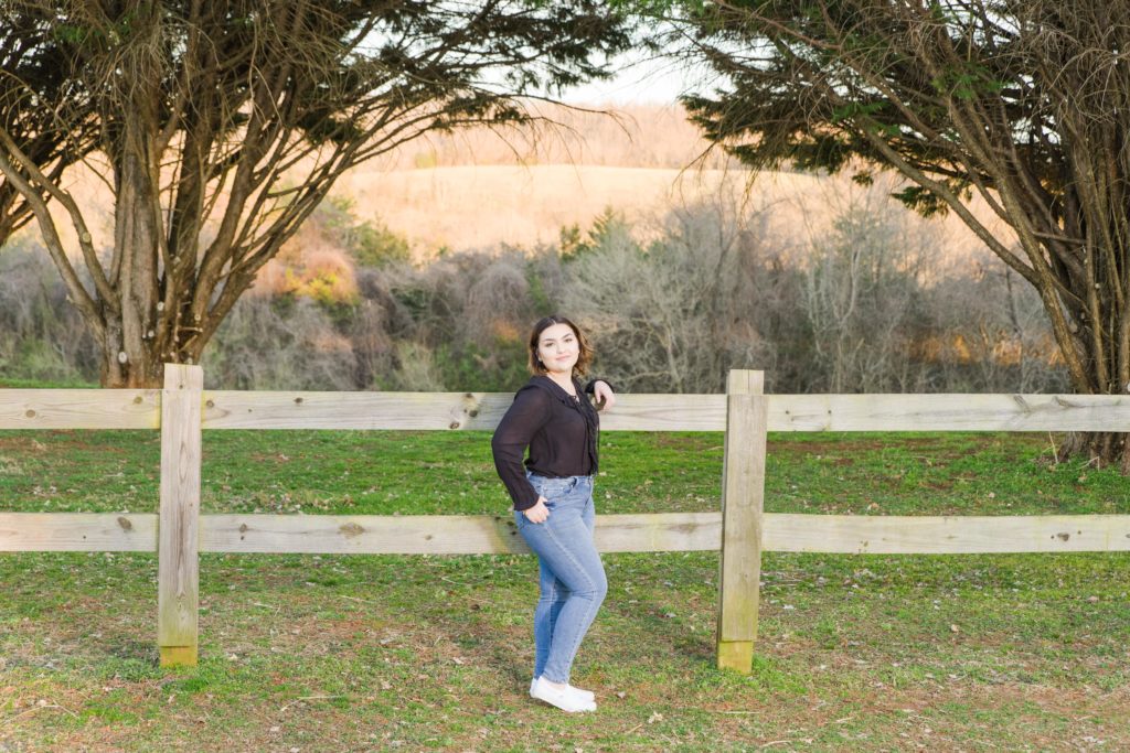 Senior portrait by fence at Penn Park with mountains in the background