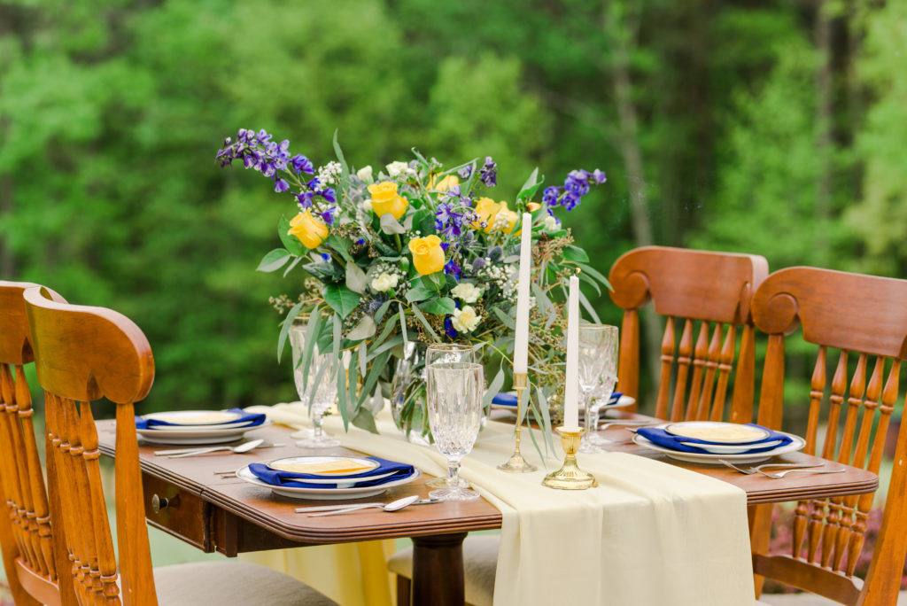 place settings and floral arrangement for blue and yellow themed reception 