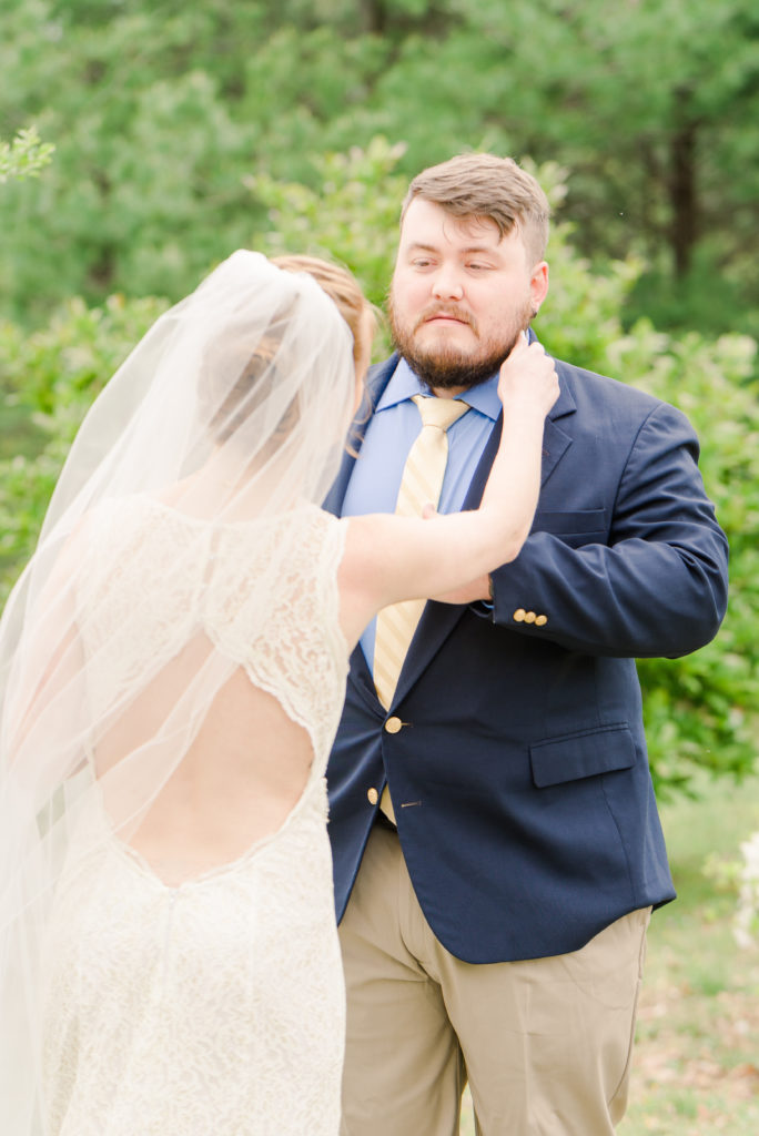 bride adjusting groom's collar during first look