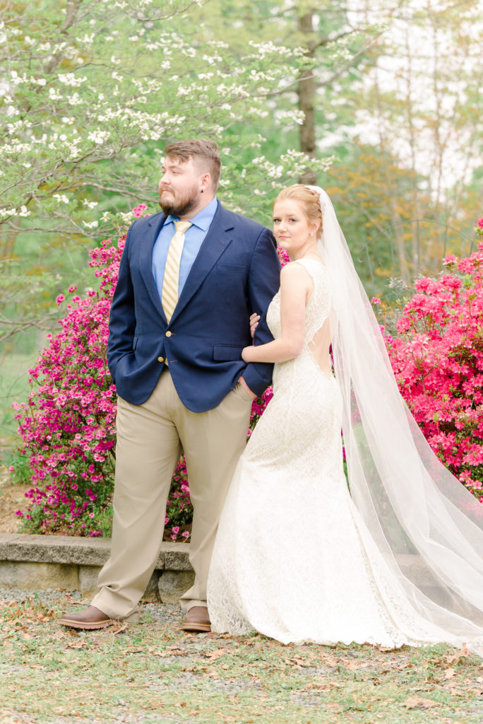 bride and groom standing in front of pink azaleas 