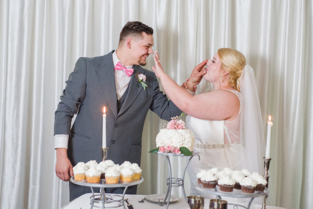 bride and groom smearing icing on each others nose after cutting cake