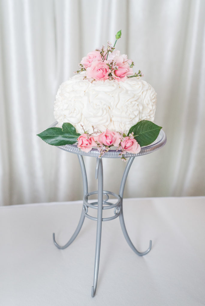 white wedding cake with pink flowers and greenery