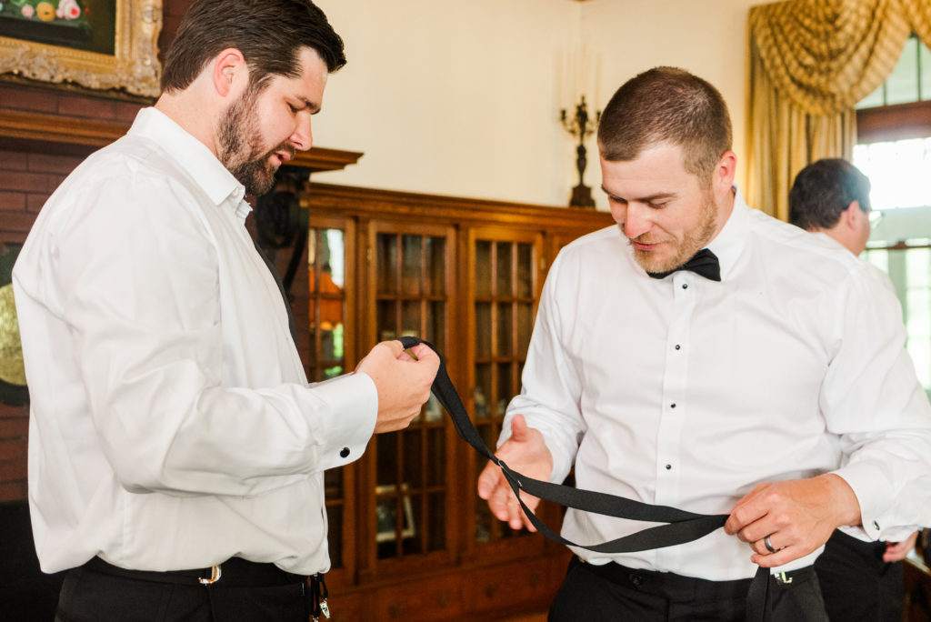 groom helping groomsmen get dressed