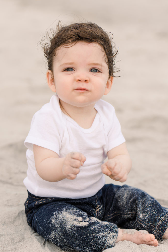 infant playing in the sand on the beach