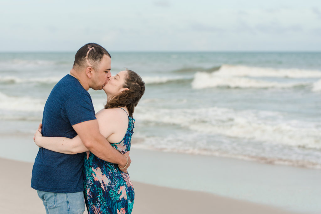 couple kissing on the beach during family session