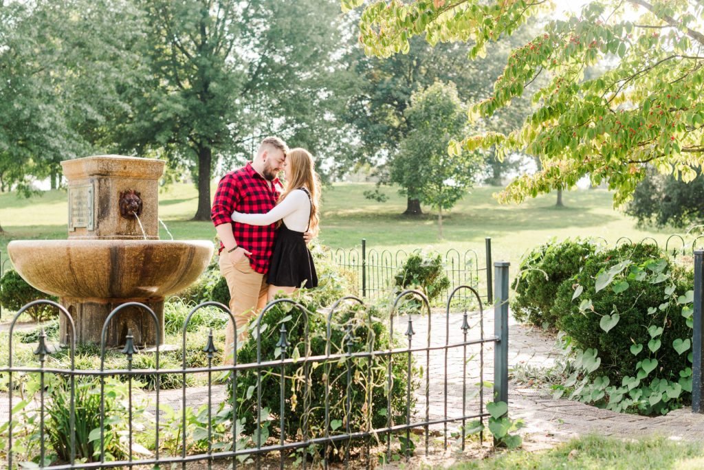 bride and groom to be kissing in front of fountain at Highland Park