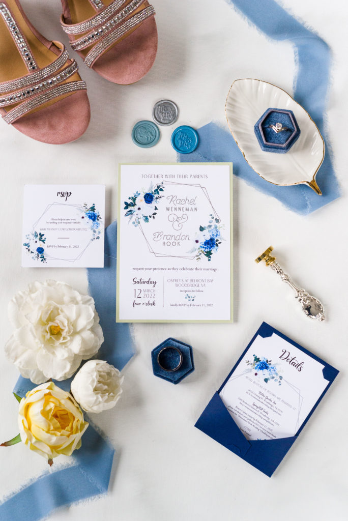 wedding flatlay with invitation suite, wax seals, wedding rings, bridal shoes and florals