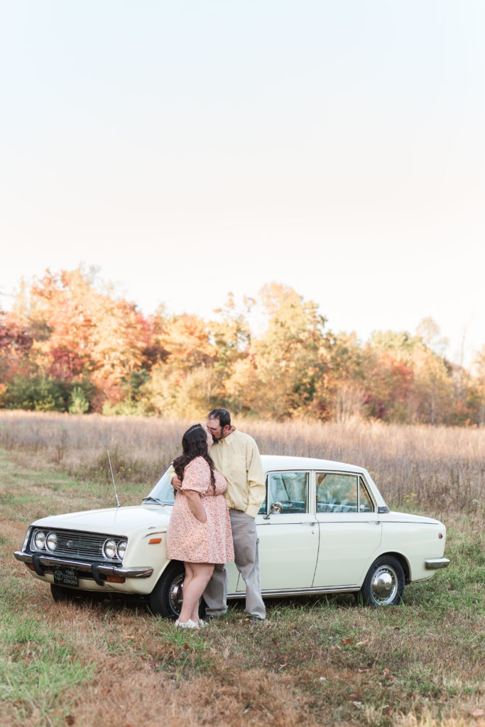 couple standing by car with fall foliage in the background