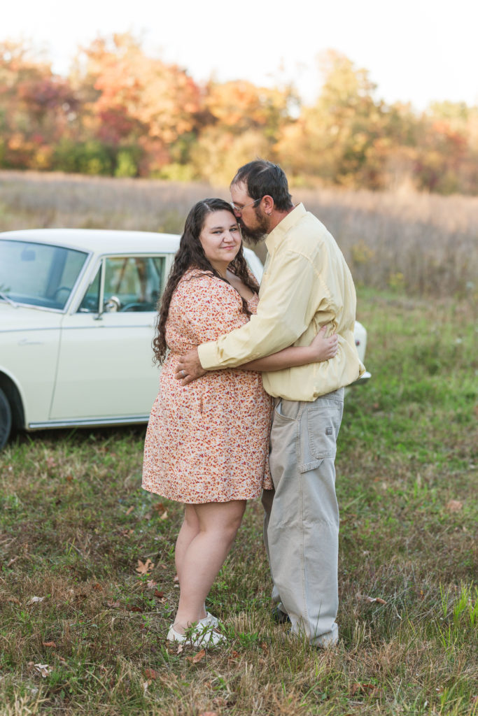 couple embracing in front of antique car