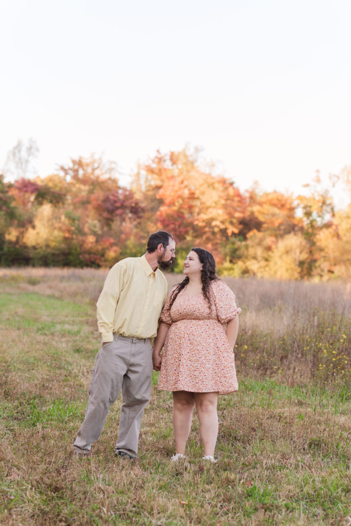 couple walking together in front of fall foliage