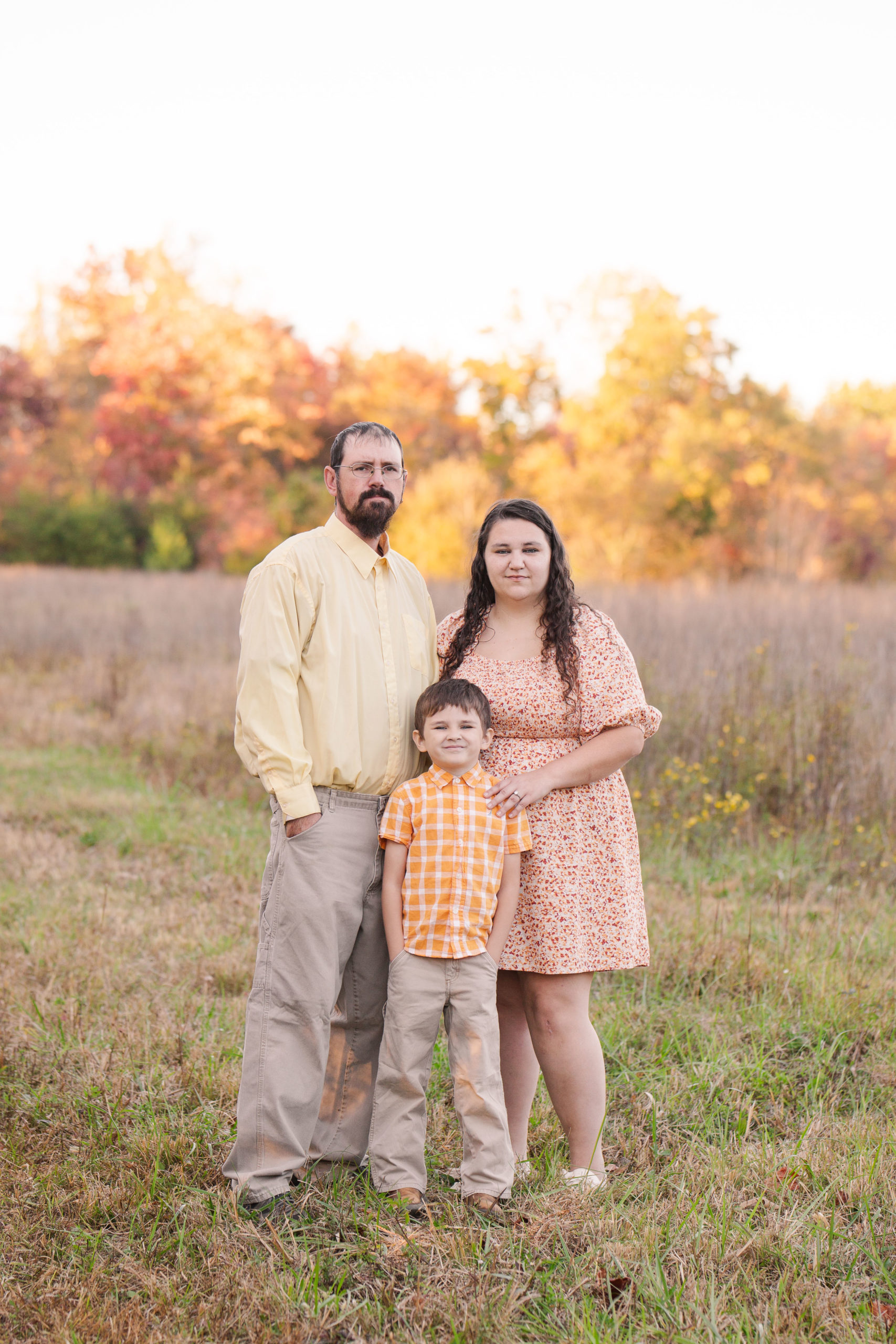 family portrait in a field with fall foliage