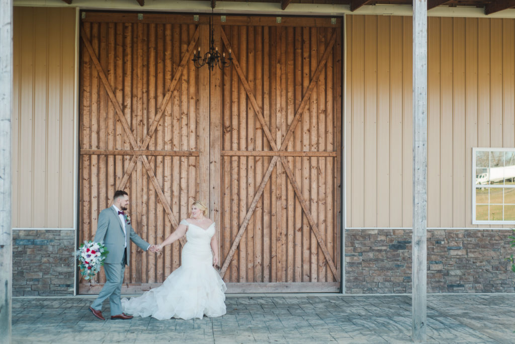 couple walking in front of barn doors at Wright Memorial Event Center