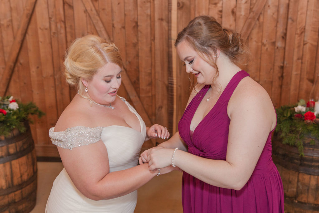 Maid of honor putting on bride's bracelet