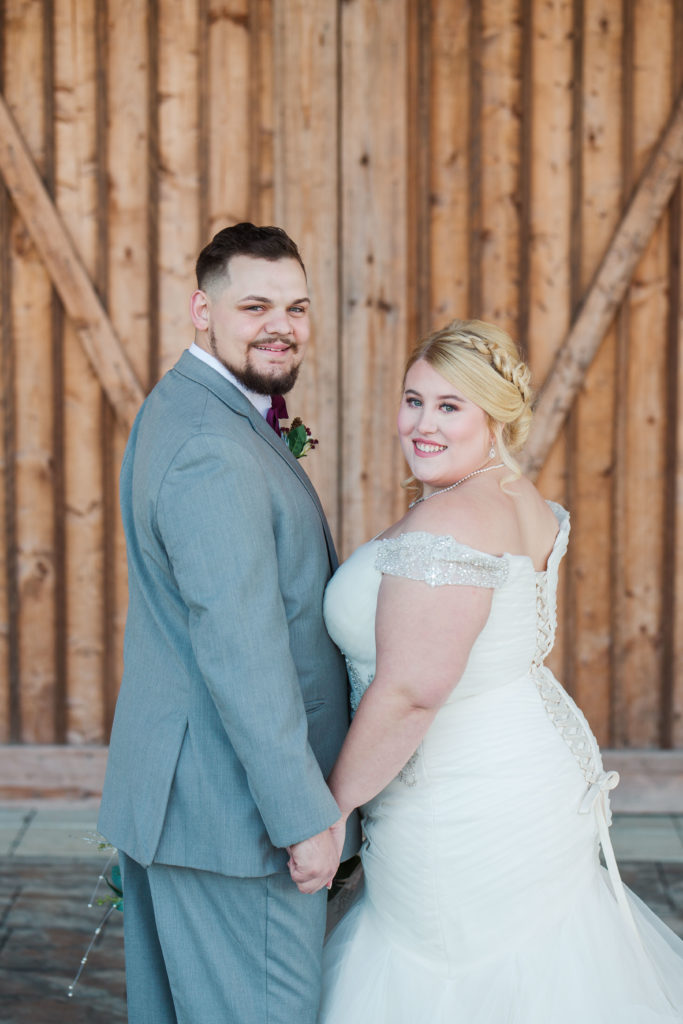 bride and groom reverse v pose in front of barn doors