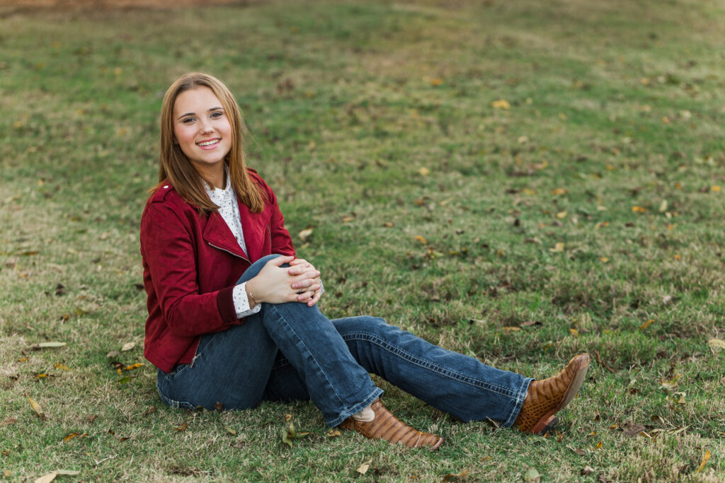 Senior portraits with red jacket, jeans and cowboy boots
