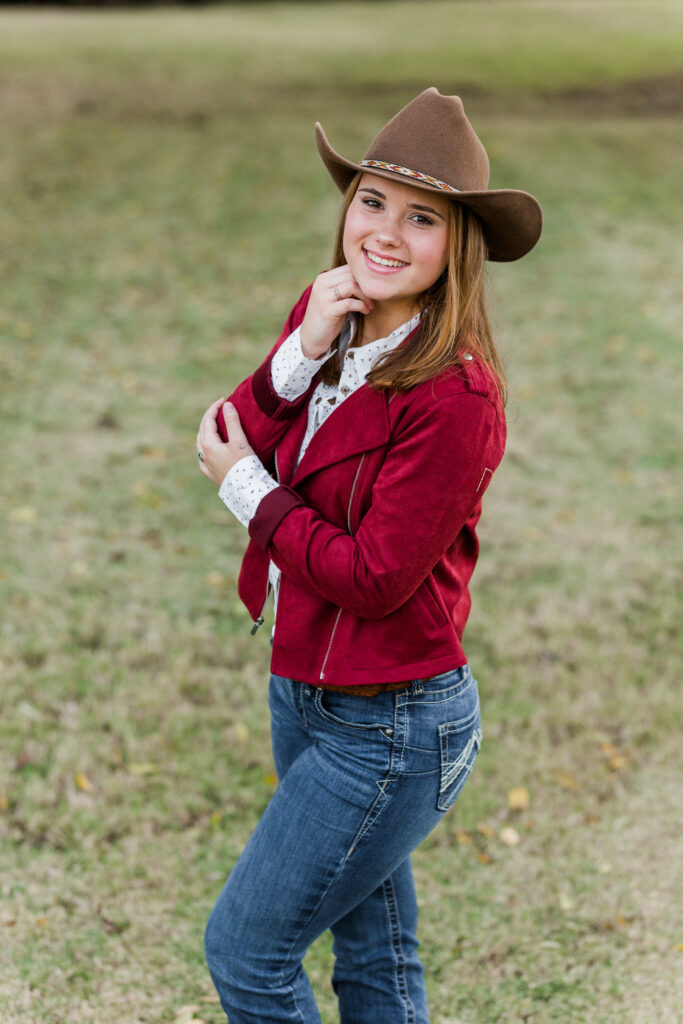 Senior portrait with red jacket, jeans and cowboy hat