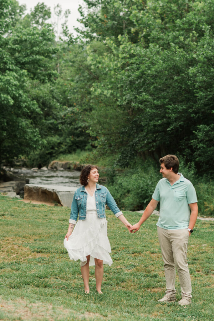 Couple looking at each other during Engagement Session in front of the South Fork Rockfish River at Bold Rock Hard Cider, Nellysford, Virginia