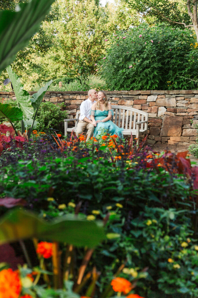 Engaged couple sitting on bench at Lewis Ginter Botanical Garden