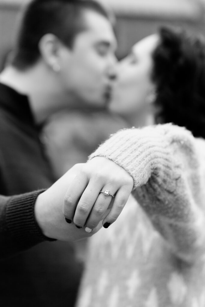 couple kissing holding out engagement ring