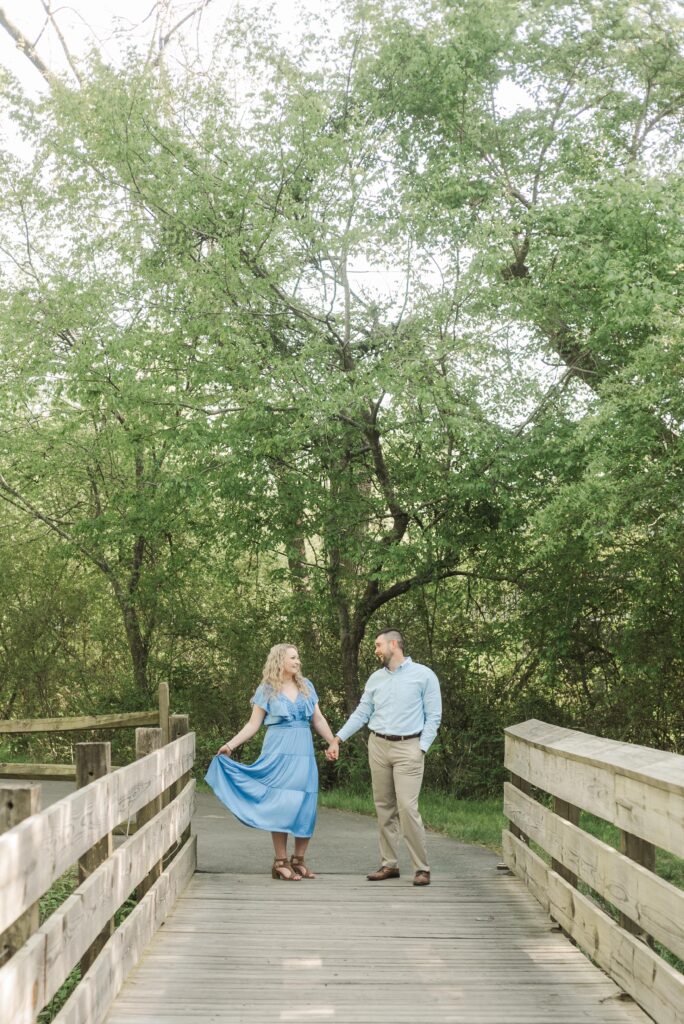 engaged couple twirling on bridge River Walk Park