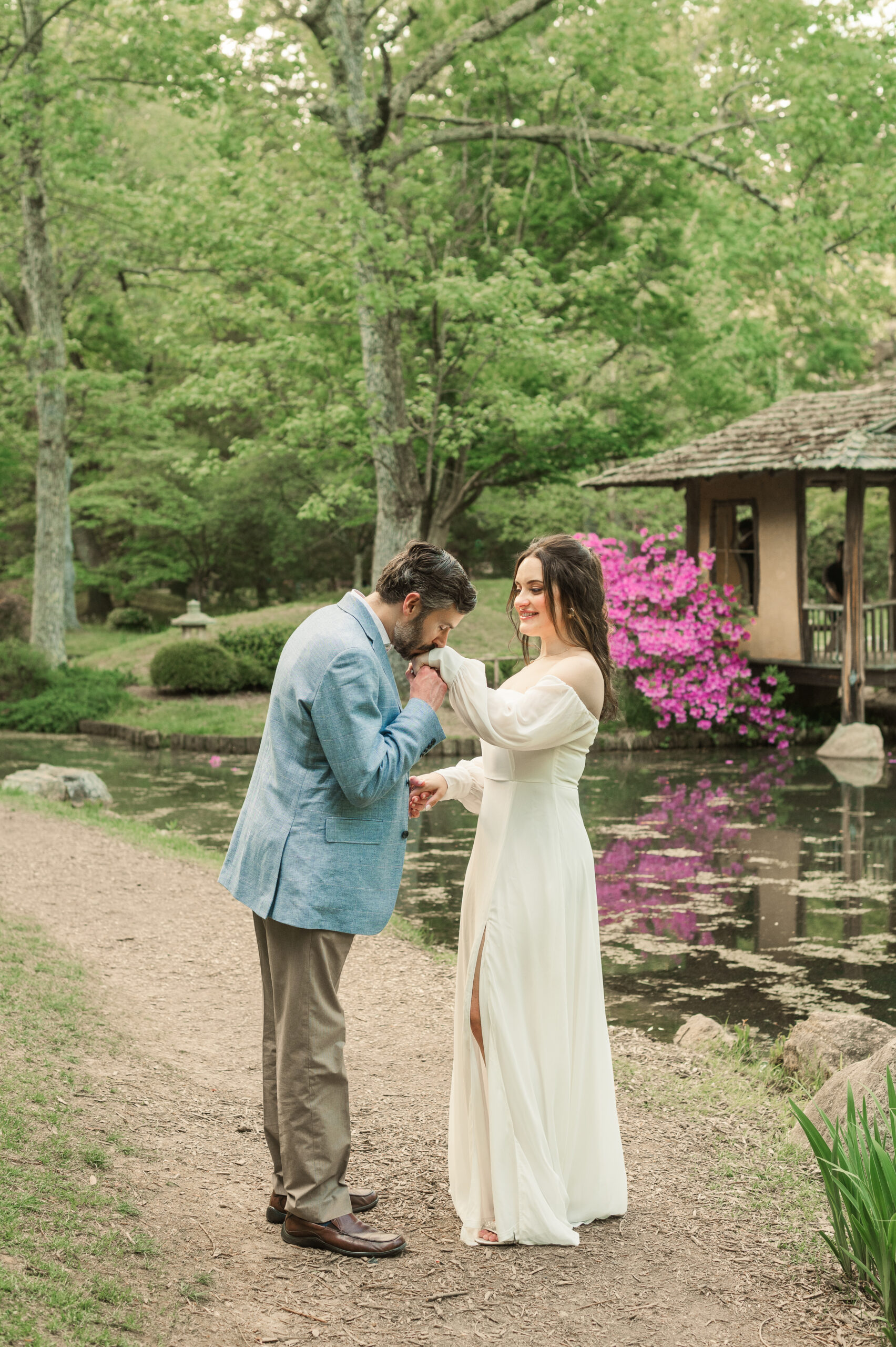 groom kissing bride's hand on path in Japanese Garden