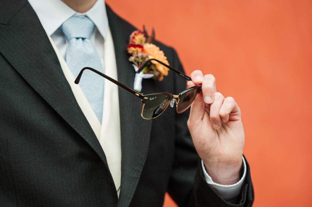 groom holding sunglasses