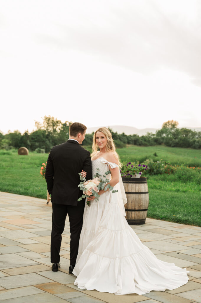 bride clutching groom's arm on patio at Blossom Ridge Farm & Vineyard