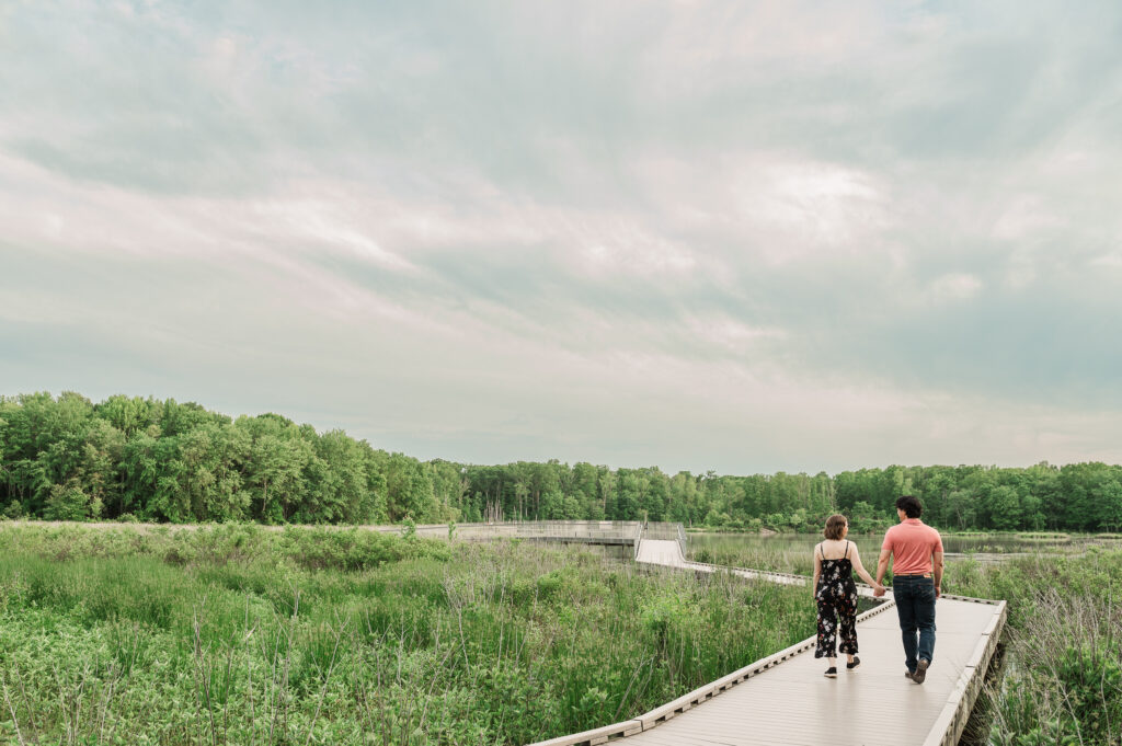 Chelsea and Alex walking hand-in-hand along the boardwalk during their Huntley Meadows engagement session in Northern Virginia.