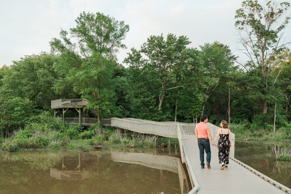 Chelsea and Alex walking hand-in-hand along the boardwalk during their Huntley Meadows engagement session in Northern Virginia.