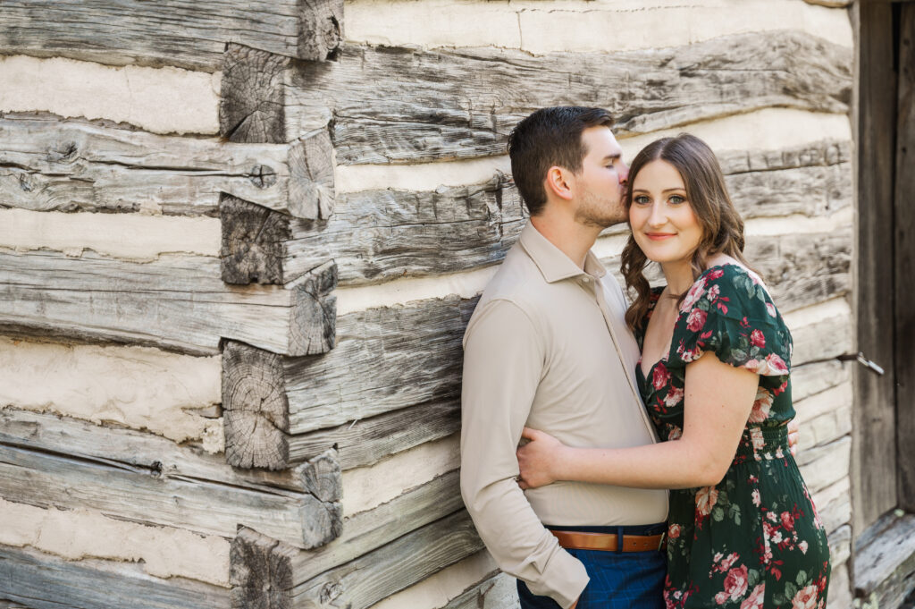 couple leaning against log cabin