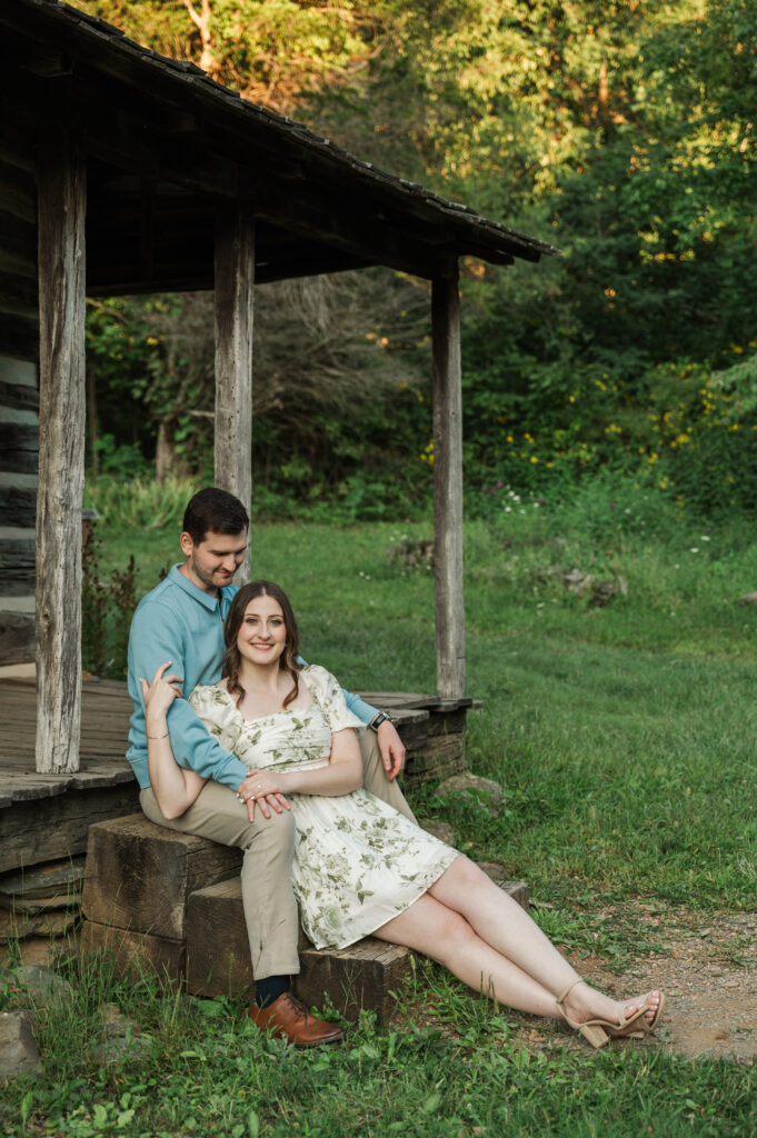 engaged couple sitting on log cabin porch