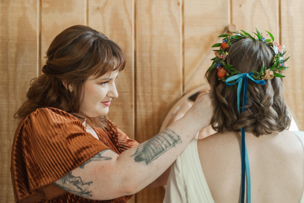 sister of the bride helping bride finish putting in earrings