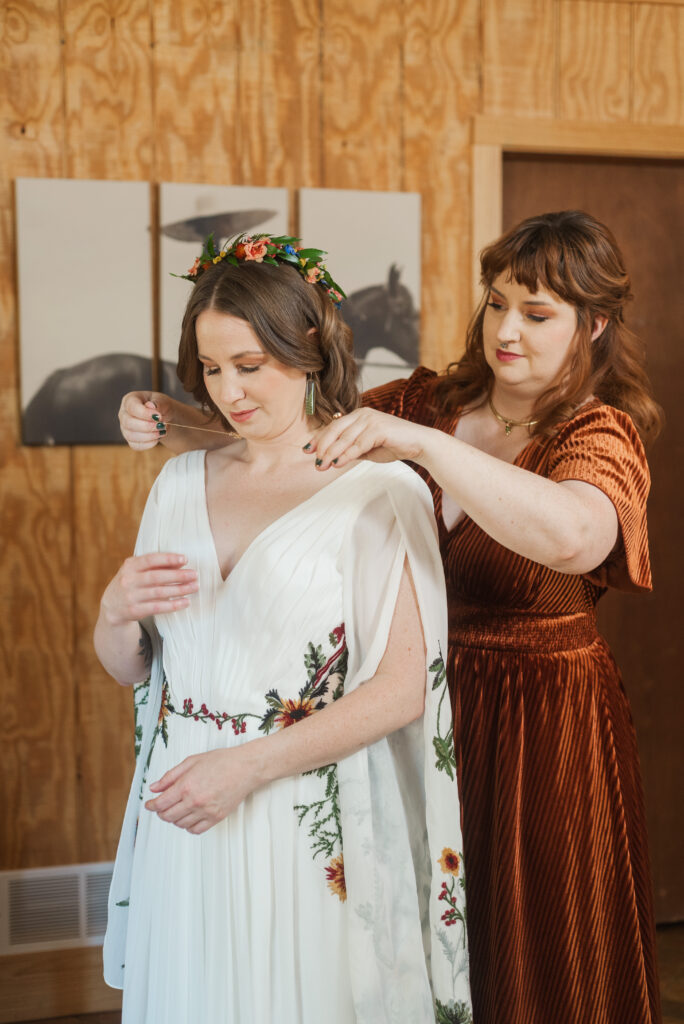 sister of bride putting on necklace