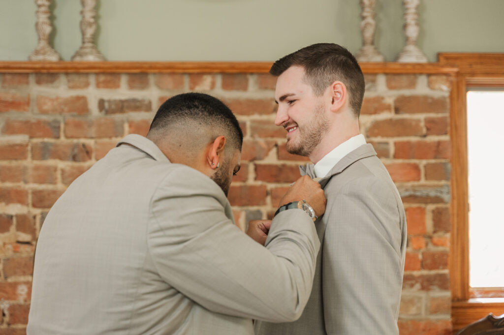 Groom Devin with best man pinning boutonniere before the ceremony.