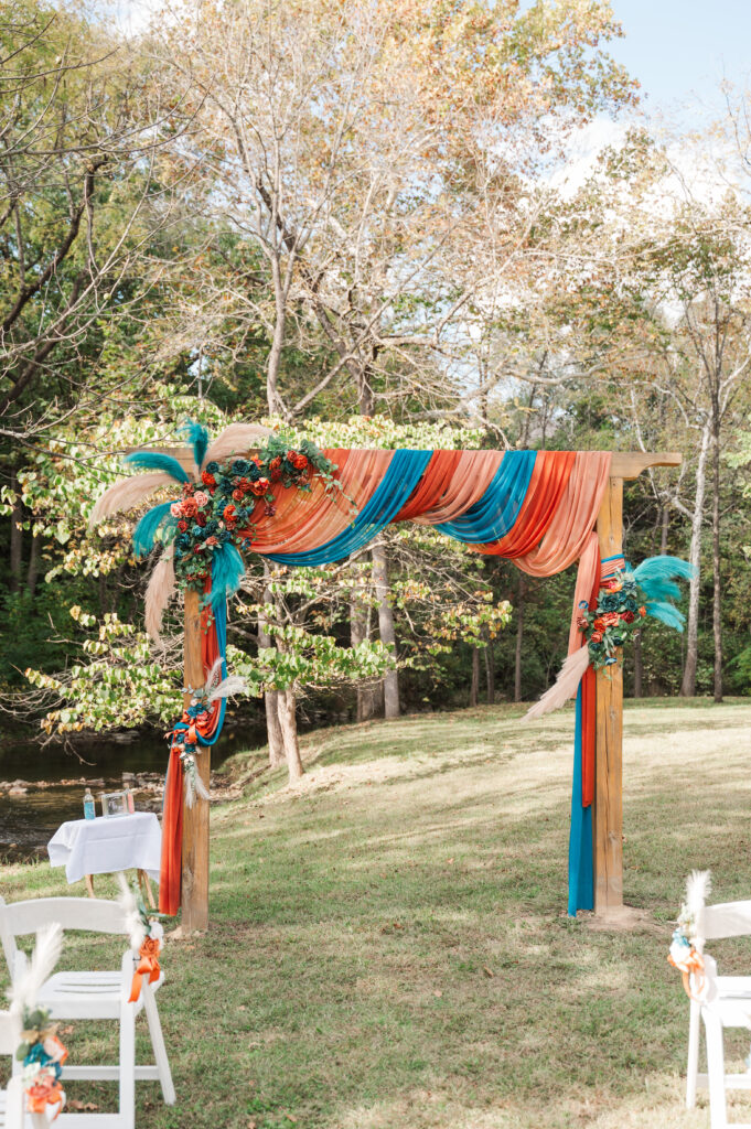 Custom wooden arch covered in colorful florals designed by a family member at Valley Mills Farm wedding.