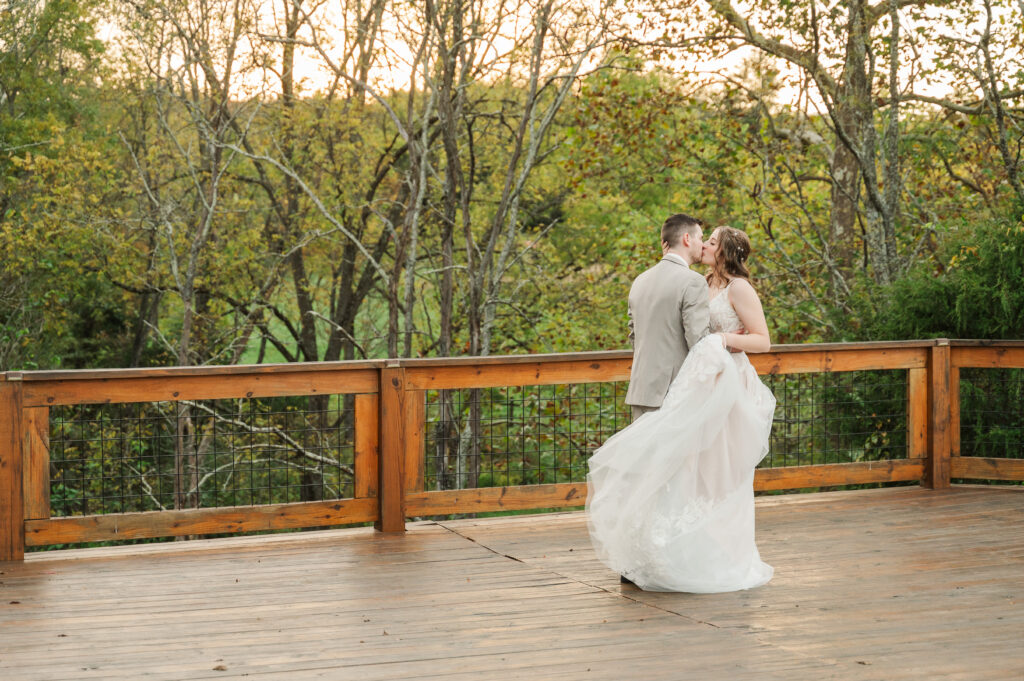 Groom holding the bride close with fall colors in the background.