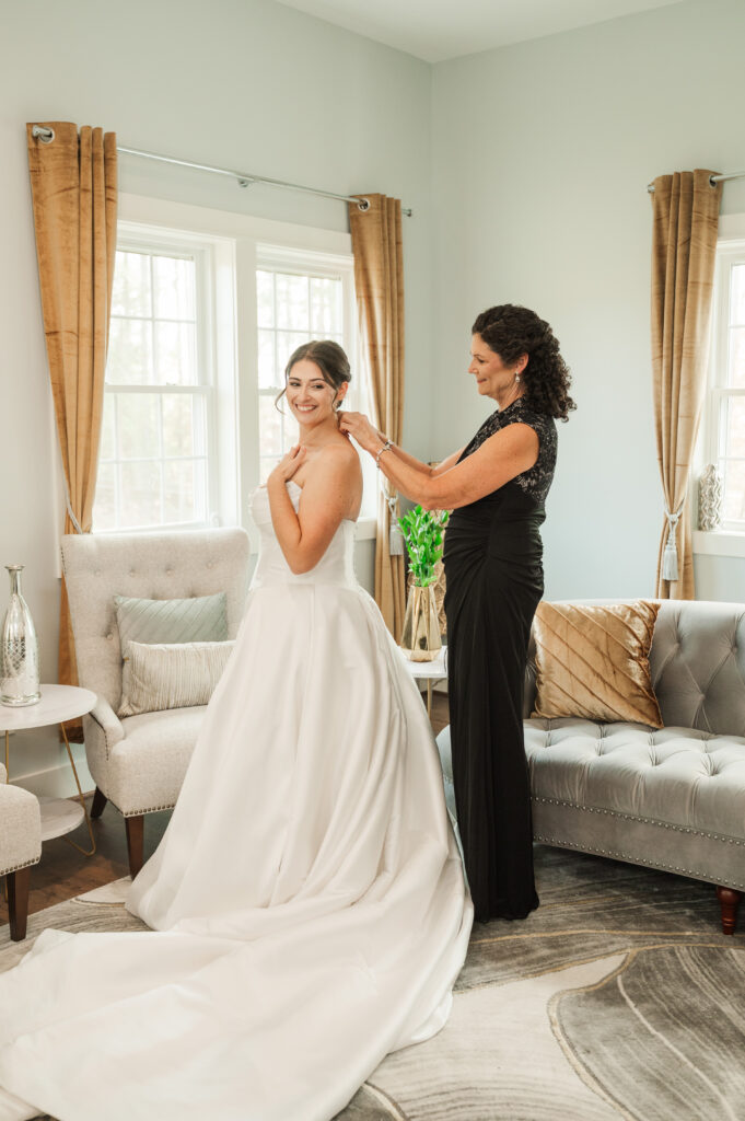 bride getting zipped into wedding dress
