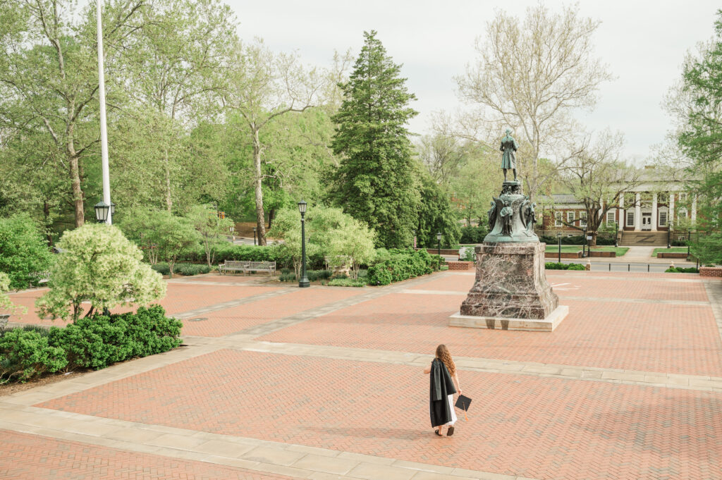 Emily walking away from Rotunda with graduation gown over shoulder and cap in hand
