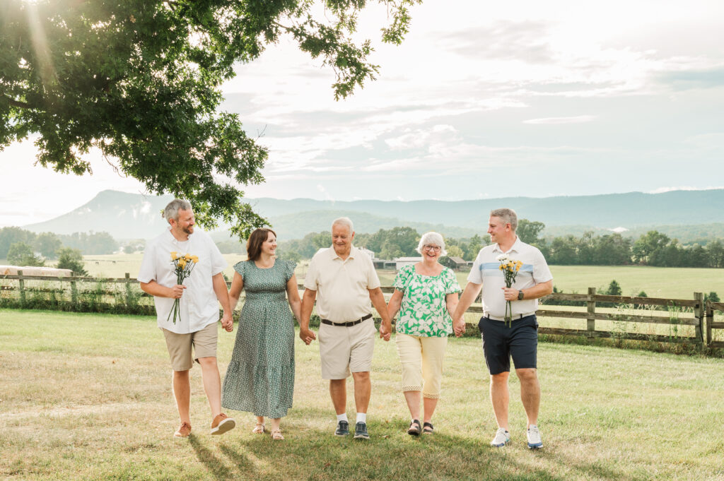 grandparents walking with their own children during extended family session with Dramatic mountain views in Virginia with sun breaking through clouds after an August thunderstorm