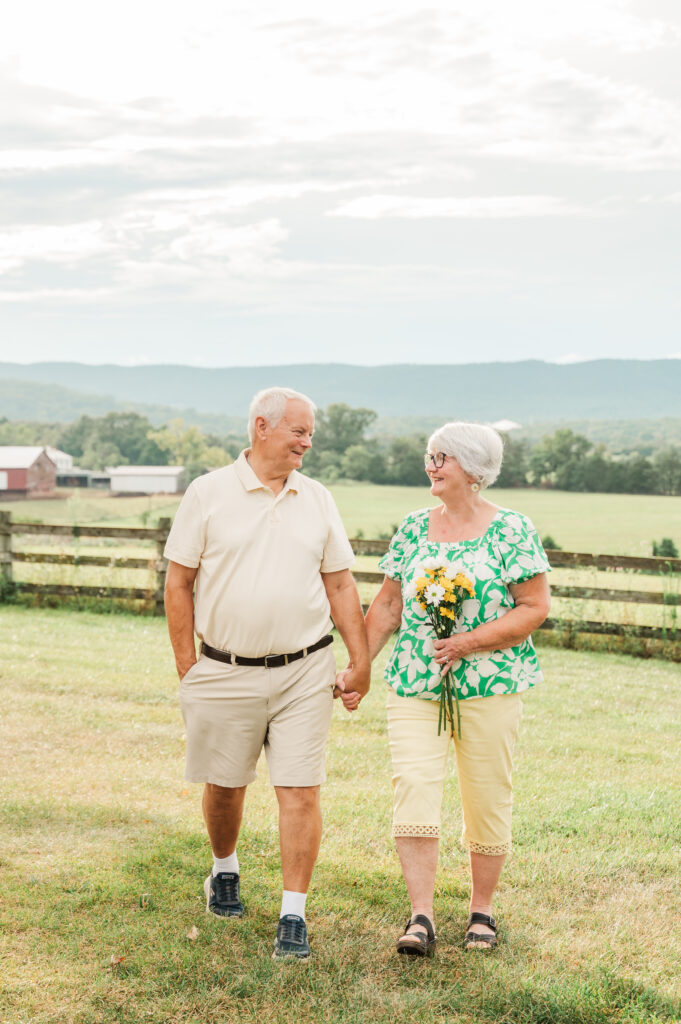 grandparents walking towards camera holding daisies to celebrate their 50th anniversary at a private estate in Elkton Virginia