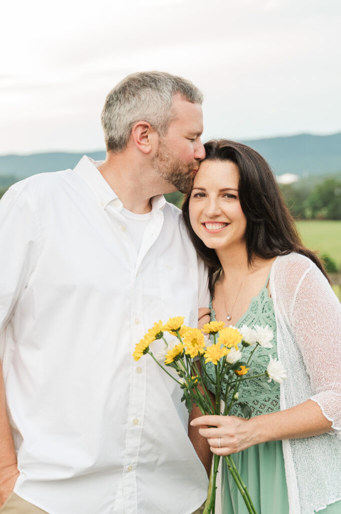 close up of parents with daisies and father kissing mom's forehead
