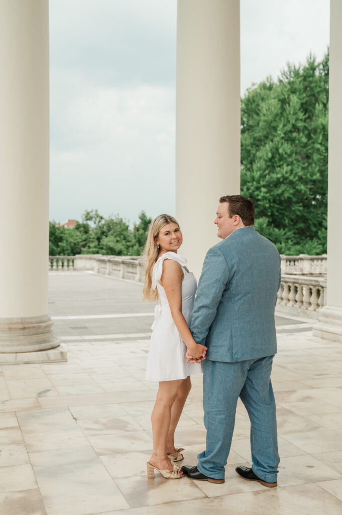 Micheala and Wade holding hands in front of the white columns at UVA